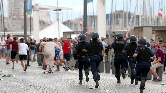 French police officers run towards football fans in the old town area of Marseille ahead of the first game in Euro 2016