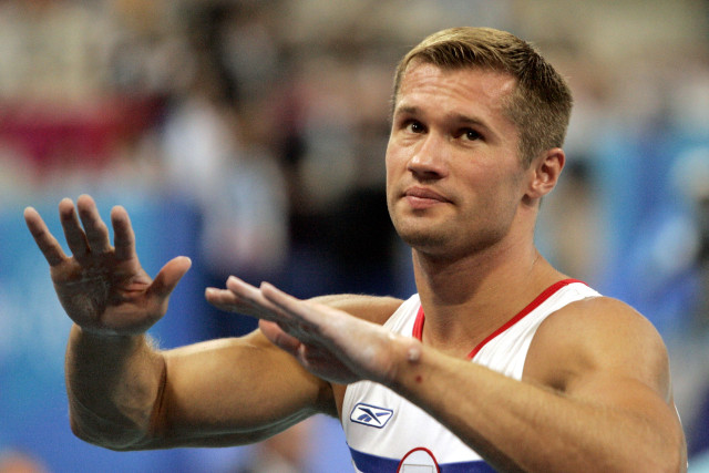 Russian gymnast Alexei Nemov tries to calm spectators booing during the men's horizontal bar final a..