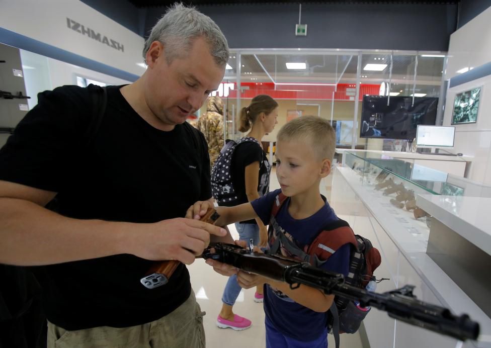 A man with a boy browse a model AK-47 assault rifle at the newly opened Gunmaker Kalashnikov souvenir store in Moscow's Sheremetyevo airport