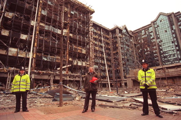 LONDON, UNITED KINGDOM - FEBRUARY 11: A picture taken 11 February 1996 shows Commander of the British Anti terorist Squad (C) flanked by two uniform officers standing in front of the building devastated by 09 February's IRA lorry bomb in London's Docklands' area. Docklands bomber James McArdle walked free of the Maze Prison, along with around 80 republican and loyalist bombers and killers, 28 July 2000 after being given the Royal Prerogative of Mercy by Ulster secretary Peter Mandelson. (Photo credit should read ANDREW WINNING/AFP/Getty Images)