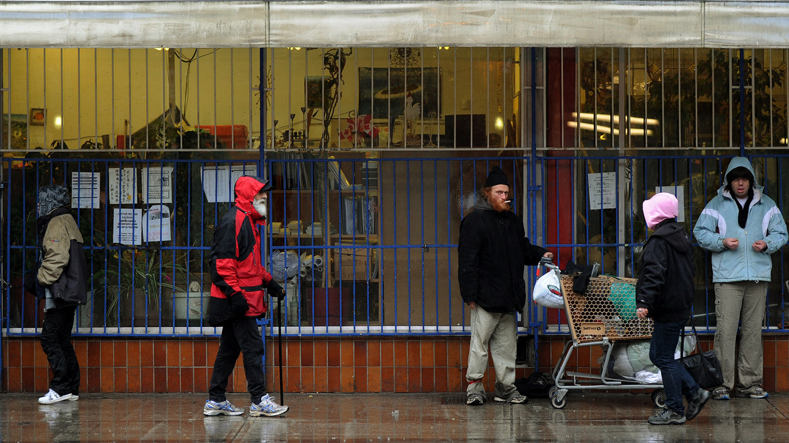 A group of homeless and poor seek shelter from the rain outside a store in the Downtown Eastside area of Vancouver on February 11, 2010. Canada is spending over two billion dollars on the Winter Olympics but just steps away from the venue for the opening ceremony sits one of the country's most notorious slums where drug addiction and prostitution are rife. The scenes of homelessness and the squalor of Downtown Eastside are not the images Olympic organizers want visitors to leave with. But the neighbourhood's close proximity to BC Place Stadium where the Olympic cauldron will be lit on Feb.12, will make it hard for visitors to miss. AFP PHOTO/Mark RALSTON (Photo credit should read MARK RALSTON/AFP/Getty Images)