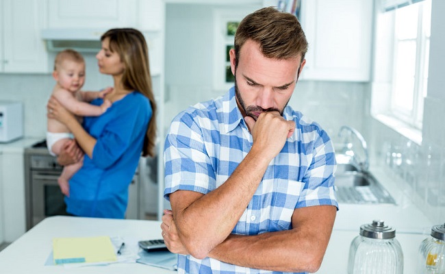 54957368 - upset man with family in background at kitchen