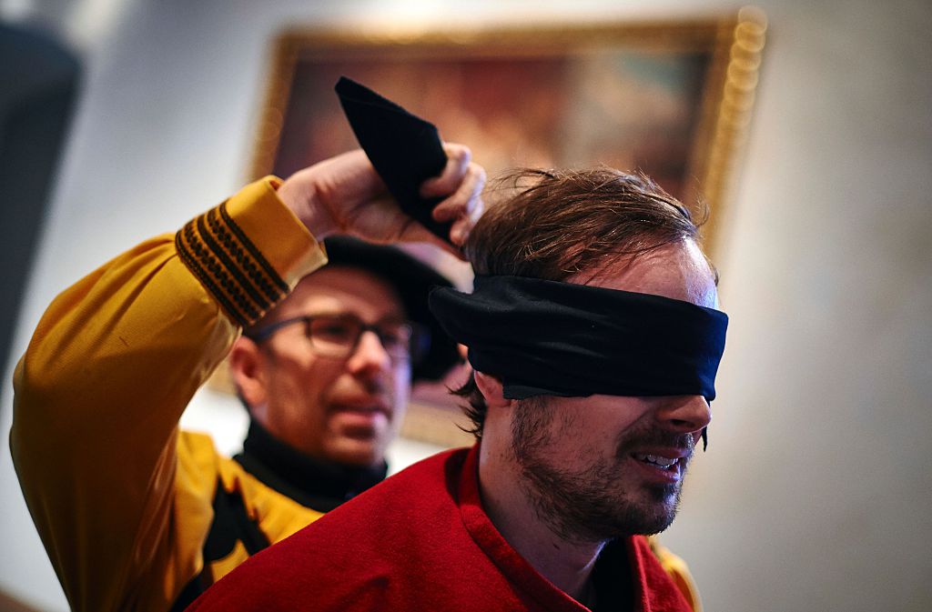A participant gets blindfolded during the 'Gansabhauet' (Cut off the goose) event, an ancient custom that takes place every year on the St Martin day, on November 11, 2016, in Sursee, central Switzerland. People of any age, armed with a rough sabre, try to sever the neck of a dead goose dangling from a rope. Participants are blindfolded under a mask depicting an enormous sun and are dressed in red coats. Since they are only allowed one strike, it is usually a long time before the goose finally falls down. / AFP / Michael Buholzer (Photo credit should read MICHAEL BUHOLZER/AFP/Getty Images)