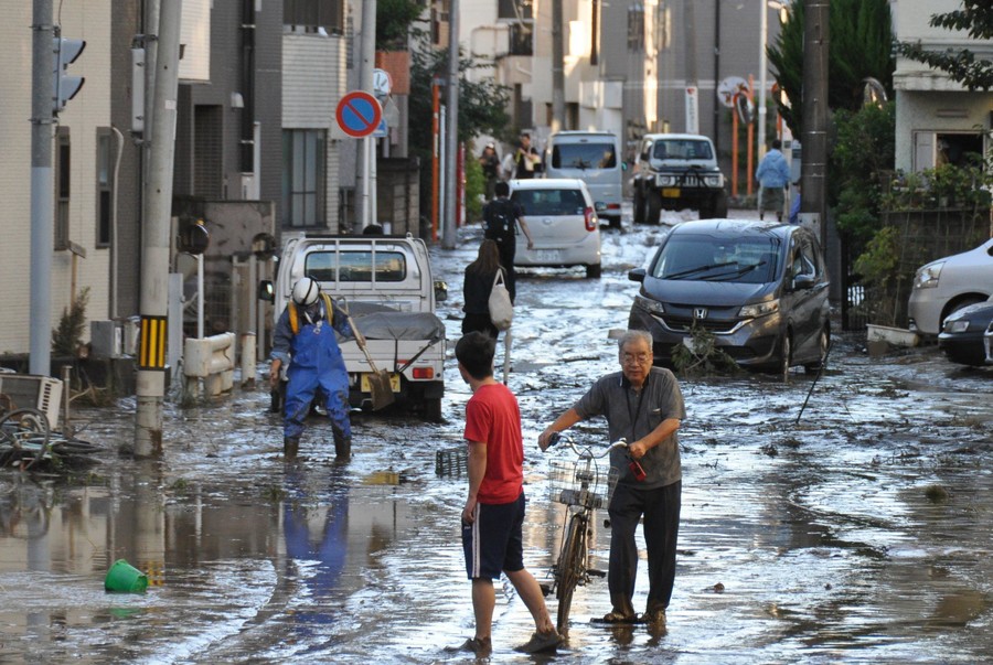 台風19号の影響により、泥がたまった道路を歩く住民（10月13日日午前、川崎市中原区）