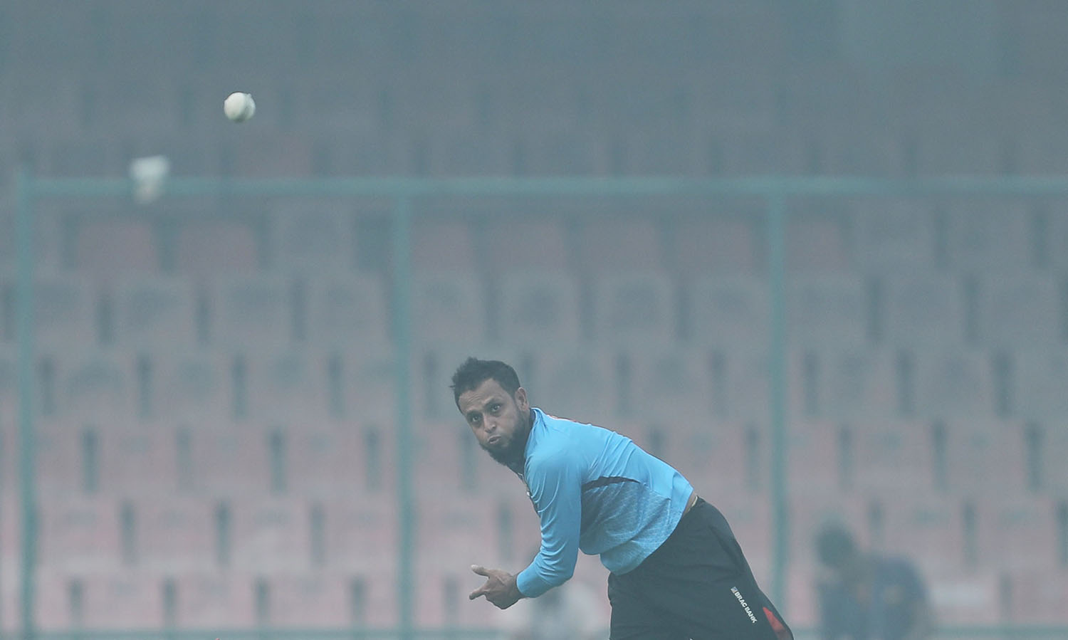Bangladesh's Arafat Sunny bowls amidst smog during a practice session ahead of their Twenty20 cricket match against India in New Delhi