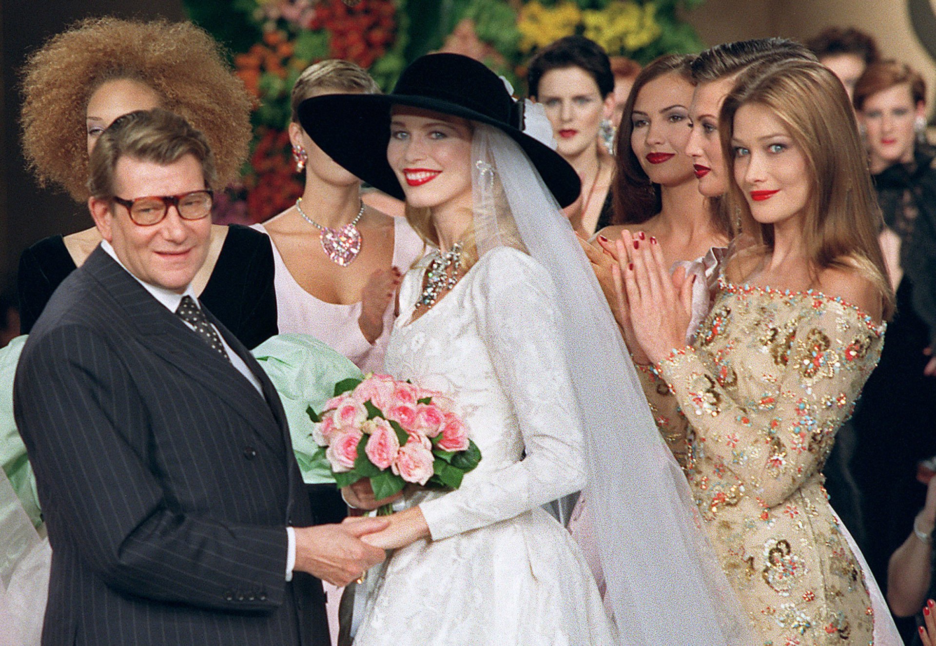 Photo taken on July 10, 1996 shows French fashion designer Yves Saint Laurent (L) posing with models Claudia Schiffer (C) and Carla Bruni during the presentation of the autumn-winter 96/97 haute couture collection in Paris. Saint Laurent, widely hailed as one of the greatest designers of the 20th century, died on June 1, 2008 in Paris. He was 71. AFP PHOTO PIERRE VERDY