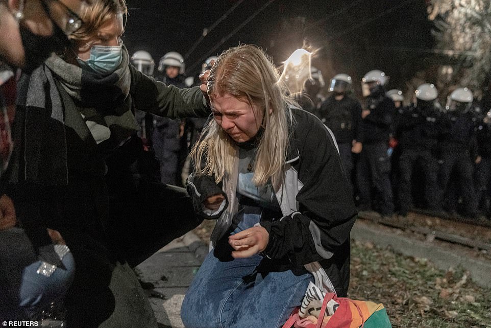 34742614-8868417-A_crying_woman_is_comforted_by_other_protesters_as_riot_police_l-a-11_1603441426991
